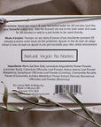 An image of the back of a white rectangular box of Só Sitz Bath Tea with black text listing directions and ingredients styled on a linen fabric background with natural elements.