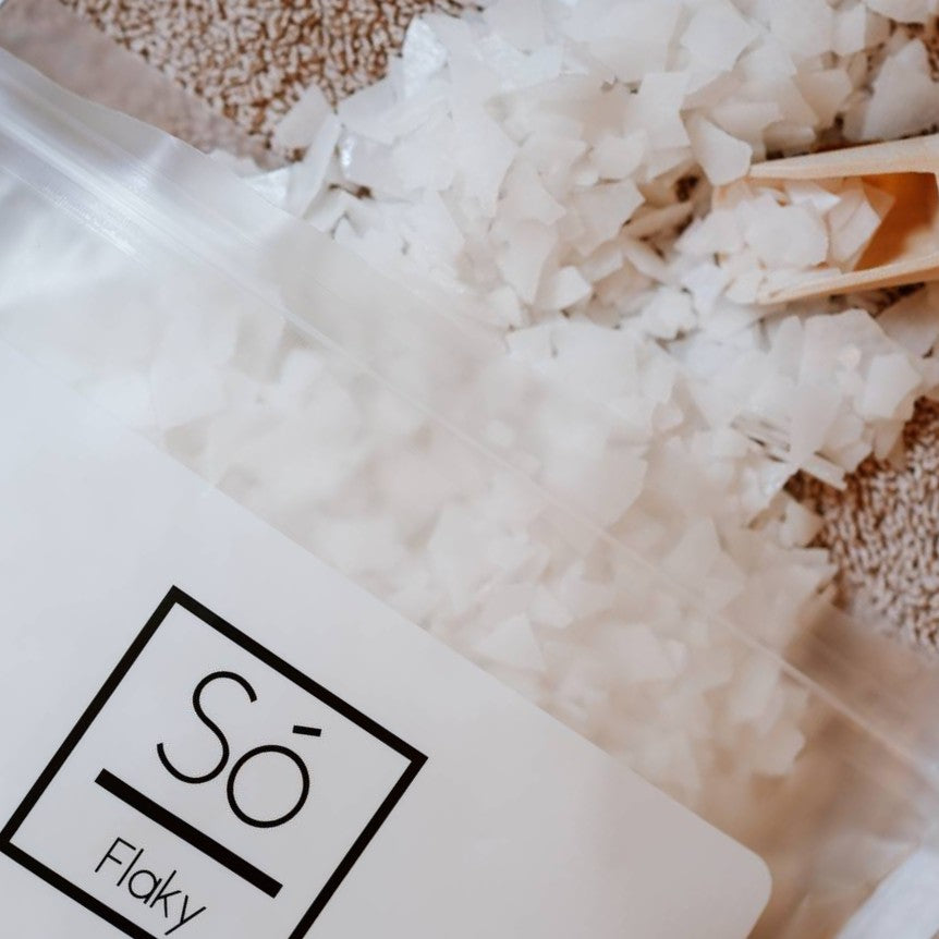 Magnesium flake salt crystals spilling out of a white and frosted bag labeled 'Só Flaky' on a textured surface.