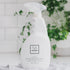 White all-purpose cleaner bottle with 'Só' branding against a blurred green plant and white tile background