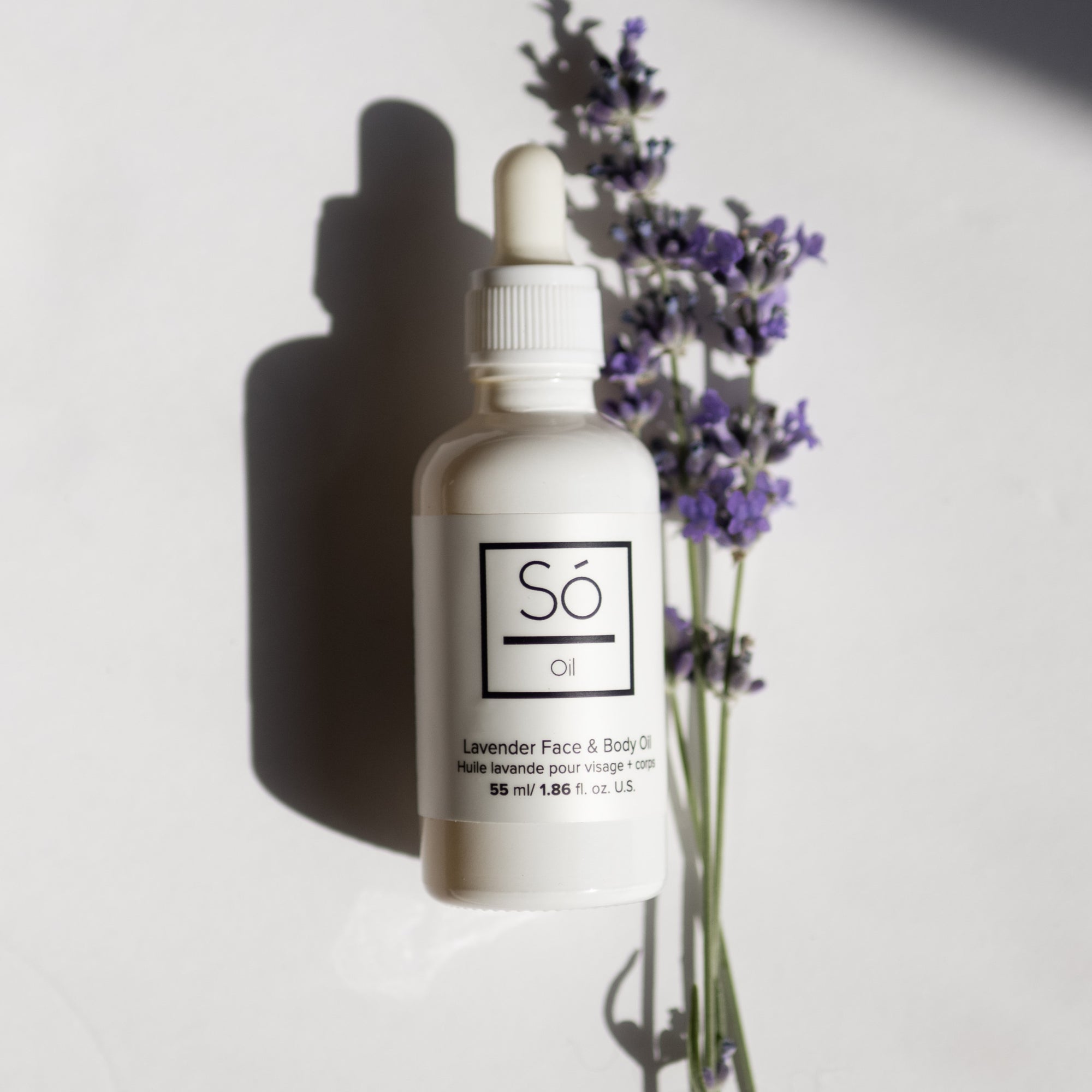 A white bottle with a dropper containing essential oil, labeled 'Só Oil', alongside lavender flowers.