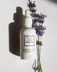 A white bottle with a dropper containing essential oil, labeled 'Só Oil', alongside lavender flowers.