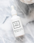 A white bottle with a dropper labeled 'Só Oil Sweet Orange" on a marble backdrop