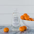 Bottle of Só Clean branded Tangerine Dish Soap with tangerines on a marble surface with a blurred light coloured background